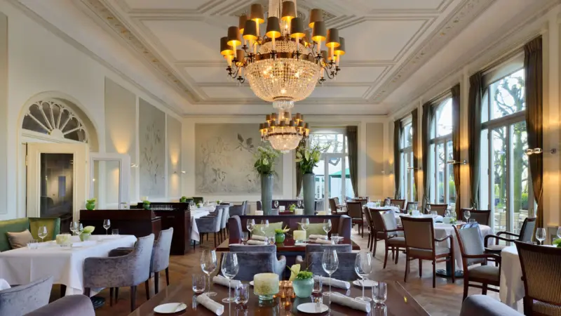 Das Jacobs Restaurant mit Tischen und Stühlen, dekoriert mit Kronleuchtern.