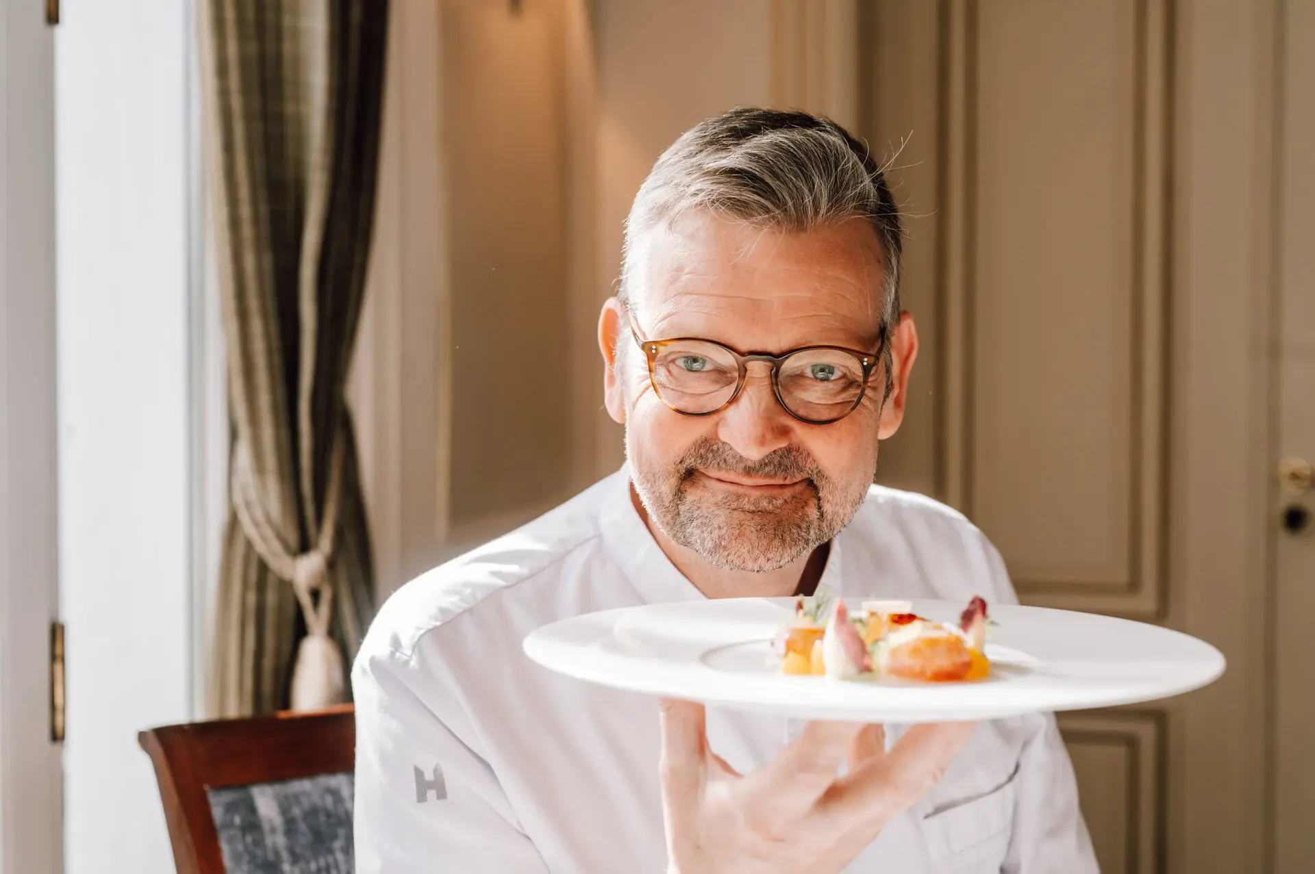 Thomas Martin Jacob Restaurant Koch Thomas Martin hält einen Teller mit Essen in die Kamera und lächelt.