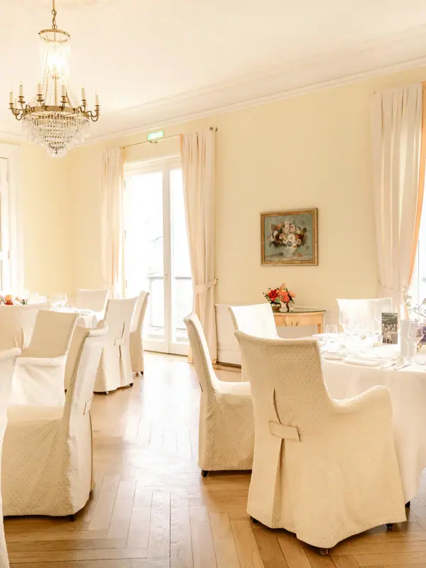 Ein Raum mit Tischen und Stühlen, elegant eingerichtet mit Tischdecken und Vorhängen.