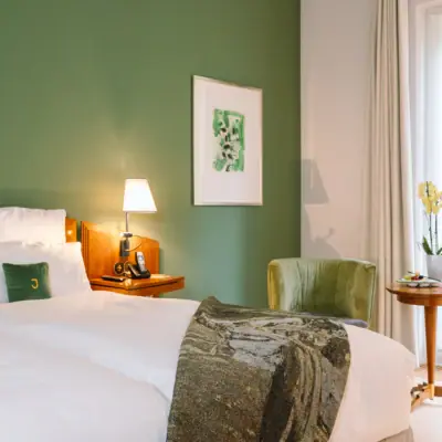 Ein Zimmer mit zwei Betten, einem Tisch und einer Lampe.