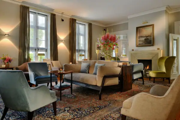 Wohnhalle des Hotels Louis C. Jacob mit gemütlichen Sesseln, Sofas und einem Kamin.