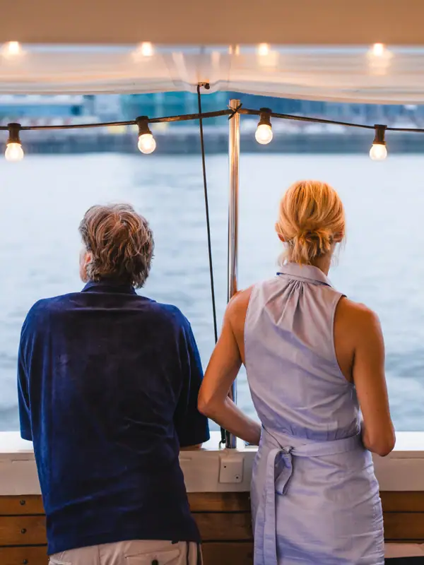 Ein Mann und eine Frau stehen an der Relig der barkasse MS Jacob und schauen aufs Wasser.