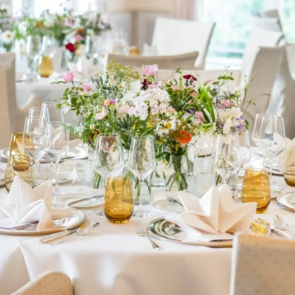 Ein festlich geschmückter Tisch mit Blumenarrangement und Weingläsern.