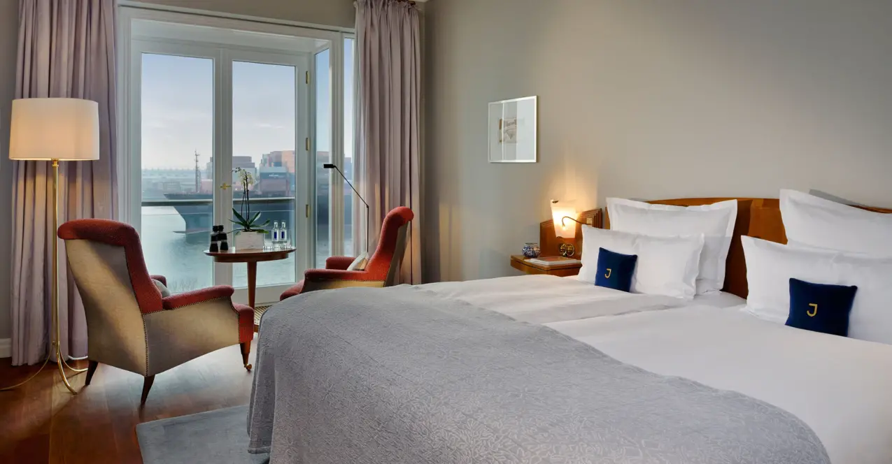 Elegantes Hotelzimmer im Louis C. Jacob mit einem Bett, Stühlen und einem Fenster mit Blick auf die Elbe.