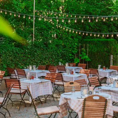 Biergarten der Weinwirtschaft Kleines Jacob mit Tische und Stühle im Freien sowie Lichterketten