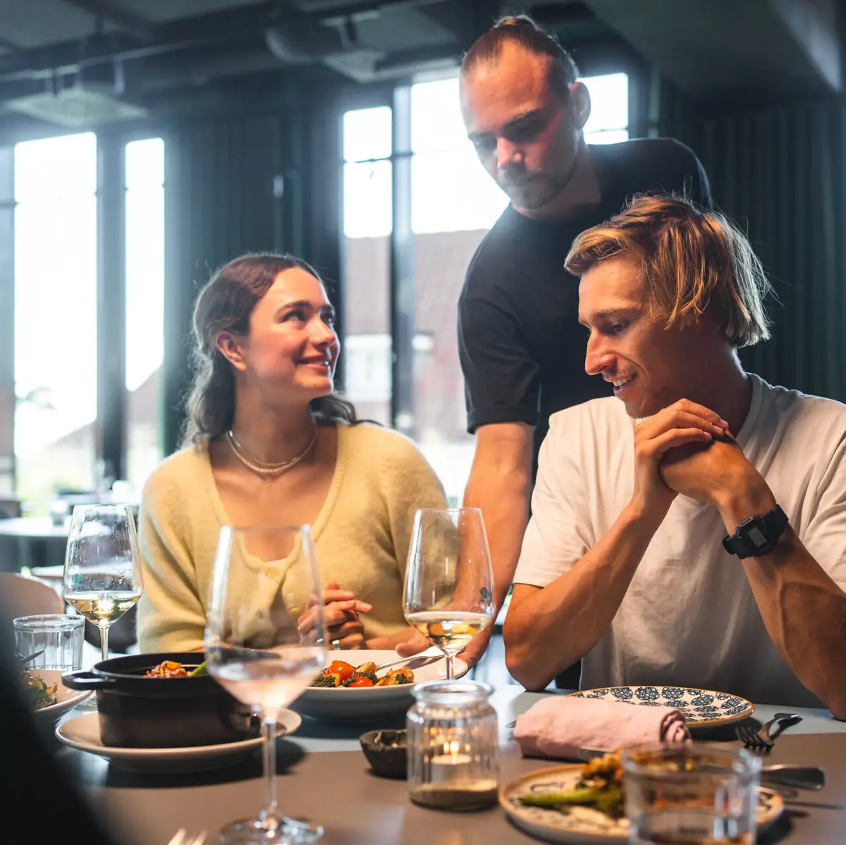Auntie Clara Restaurant Ein Mann und eine Frau sitzen in einem Restaurant und werden von einem Kellner bedient.