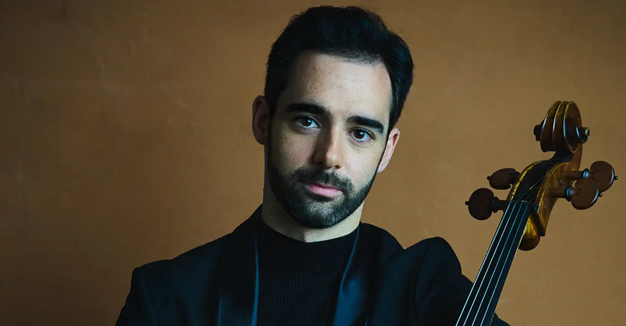 Pablo Ferrández in schwarzem Anzug und mit seinem Cello im Arm. 