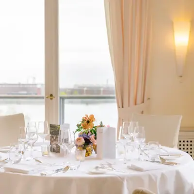 Ein festlich gedeckter Tisch für ein Abendessen mit Tischdecke, Geschirr und Vase als Mittelpunkt.