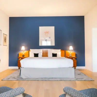 Zimmer im Hotel Louis C. Jacob mit einem Bett vor einer blauen Wand mit Gemälde.