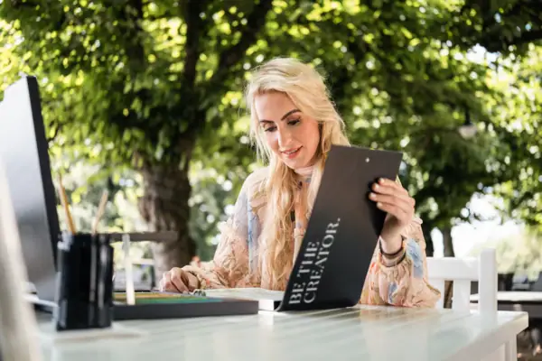 Eine Frau sitzt an einem Tisch und liest eine Speisekarte.