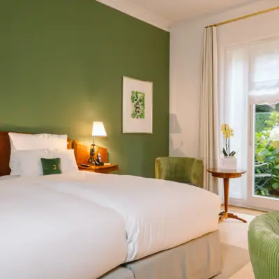 Zimmer im Hotel Louis C. Jacob mit einem Bett vor einer grünen Wand und einem Gemälde.