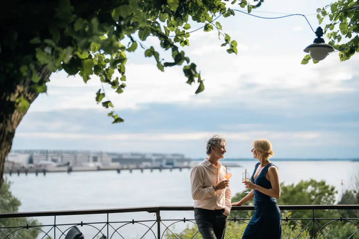 Aussicht Lindenterrasse Ein Mann und eine Frau stehen auf einem Geländer an einem Gewässer.
