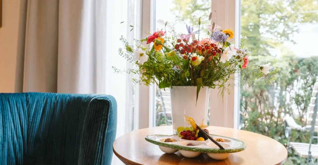 Eine Vase mit Blumen auf einem Tisch in einem Hotelzimmer im Louis C. Jacob..