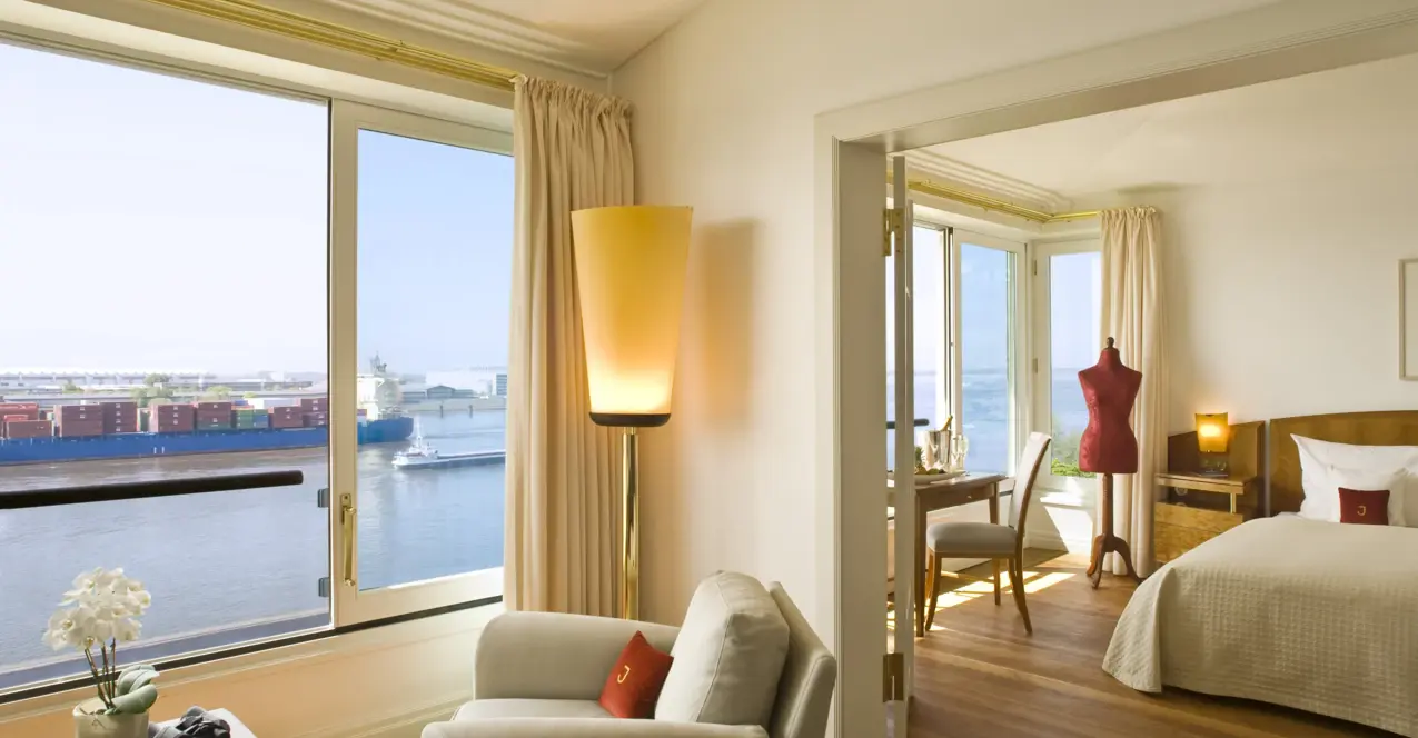 View into the bedroom of the Elbe suite in the Hotel Louis C Jacob Hamburg with a large window overlooking the Elbe.