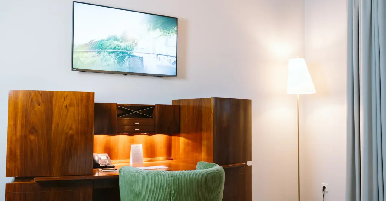 Schreibtisch mit einem Fernseher an der Wand in einem Hotelzimmer im Louis C. Jacob Hamburg.