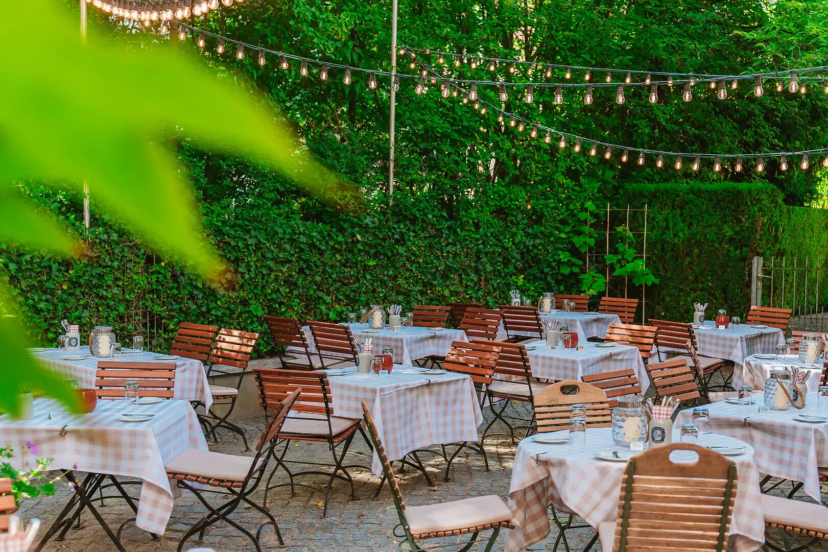 Garten das Kleine Jacob Biergarten der Weinwirtschaft Kleines Jacob mit vielen Tischen und Stühlen sowie Lichterketten.
