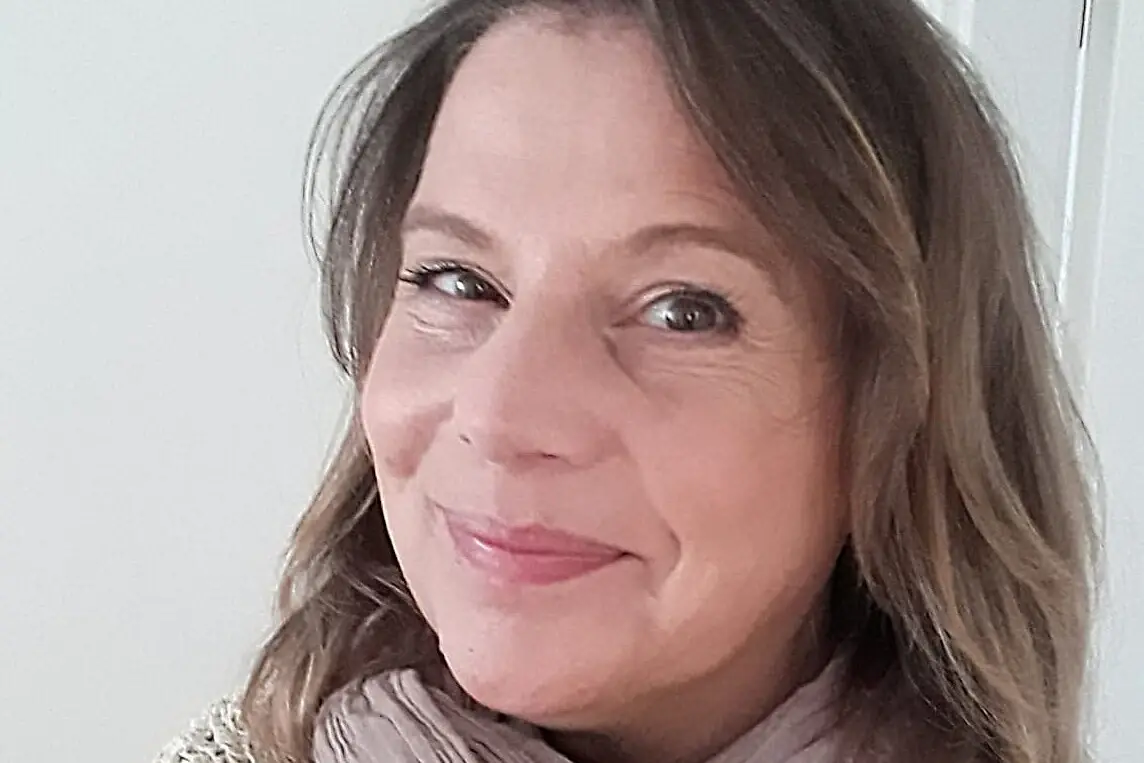 Eine Frau lächelt für ein Selfie und trägt einen Schal.