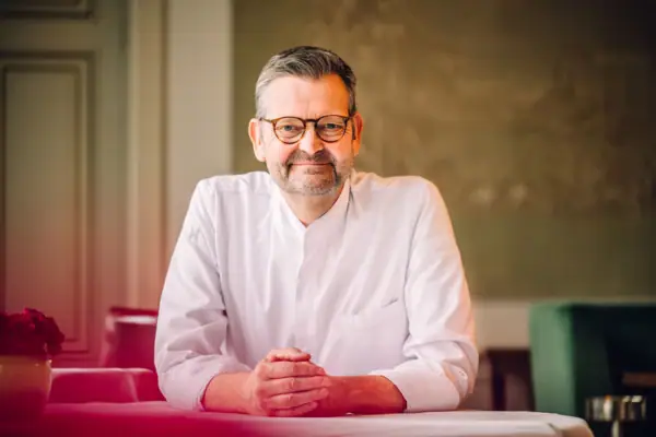 Mann sitzt am Tisch und lächelt offen 