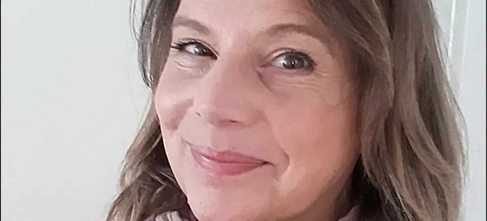 Eine Frau lächelt für ein Selfie und trägt einen Schal.