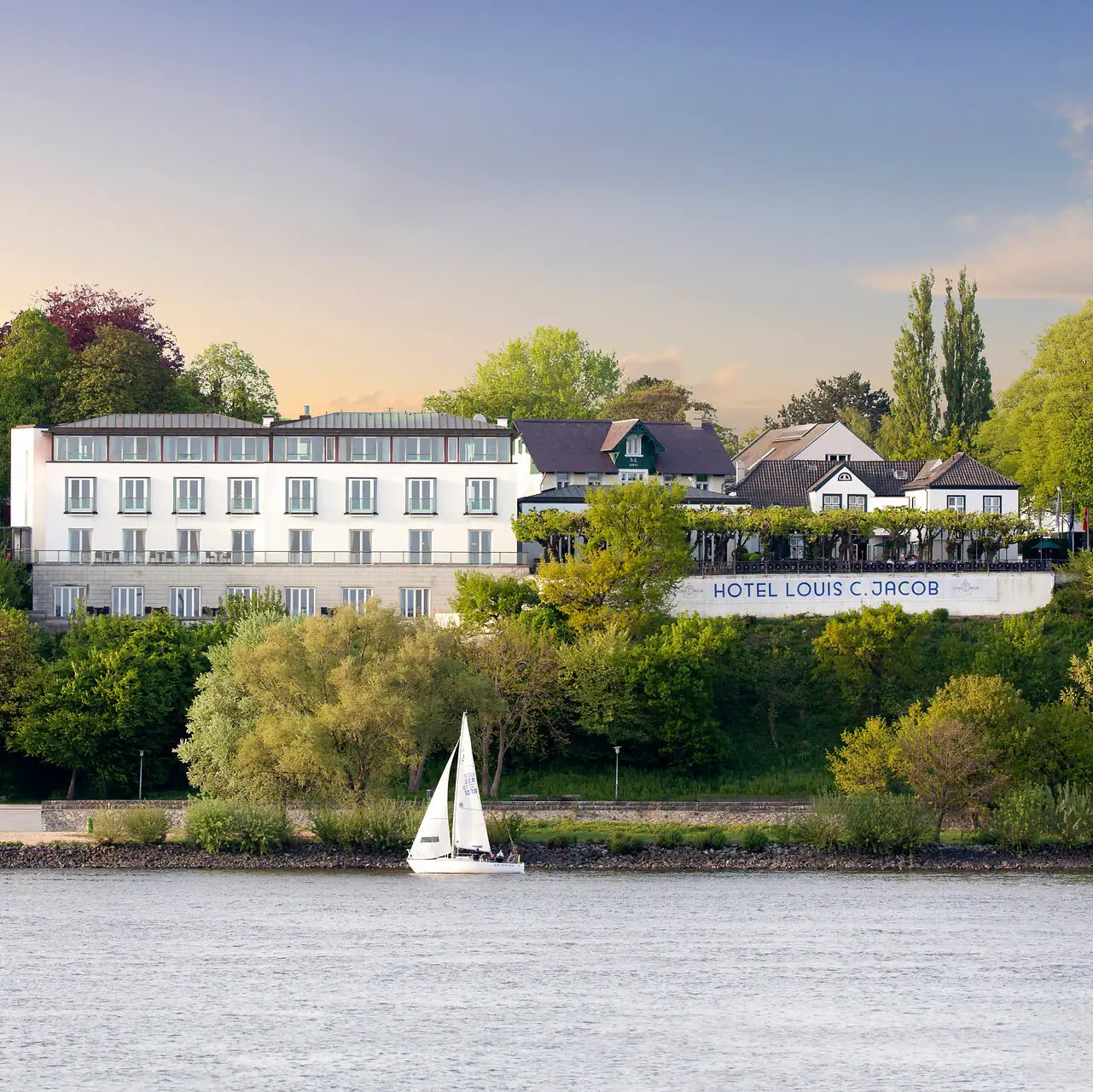Das Louis C. Jacob Hotel an der Elbe mit einem Segelboot davor im Wasser
