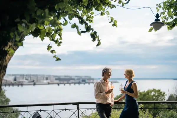 Aussicht Lindenterrasse Ein Mann und eine Frau stehen an einem Geländer vor einem See.