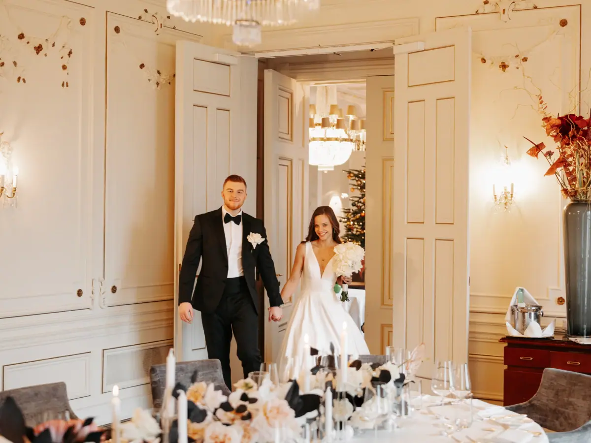 Ein Hochzeitspaar stehet neben einem Tisch mit Blumen.