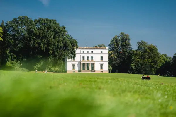 Jenischhaus im Jenischpark Weißes Gebäude inmitten eines grasbewachsenen Feldes