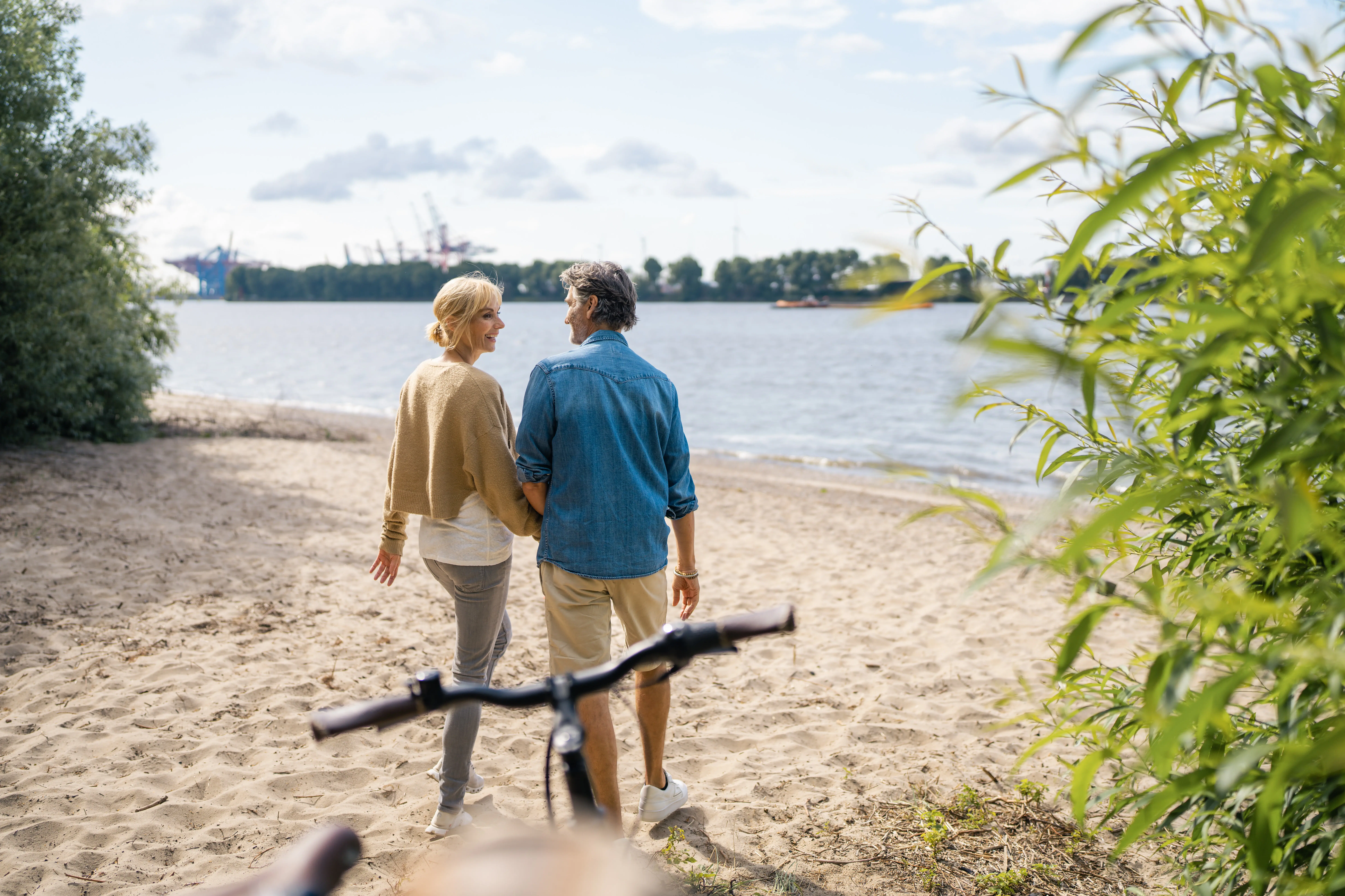 Eine Frau und ein Mann stehen an einem Strand und schauen aufs Wasser.
