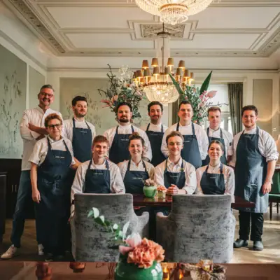 Team steht vor Kronleuchter und lächelt in die Kamera