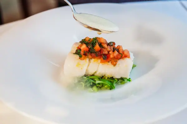 Eine Person hält einen Löffel über ein Gericht.