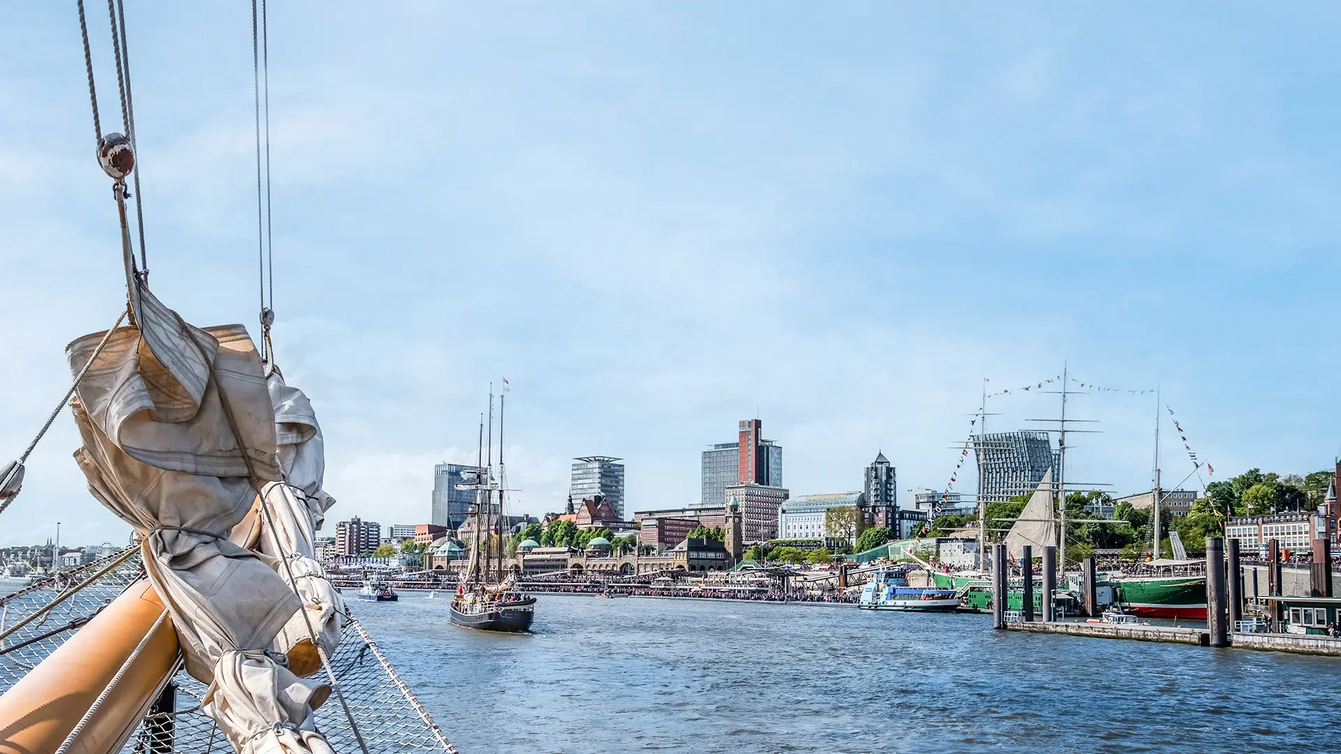 Eine Aussicht vom Buck eines Schiffes auf die Elbe und den Hamburger Hafen bei strahlendem Sonnenschein. 