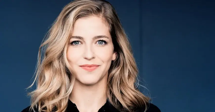 Karina Canellakis mit blonden Haaren und blauen Augen, lächelnd in einem Portrait.
