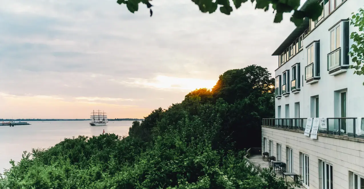 Ein Gebäude am Ufer eines Sees mit einem Boot auf dem Wasser.