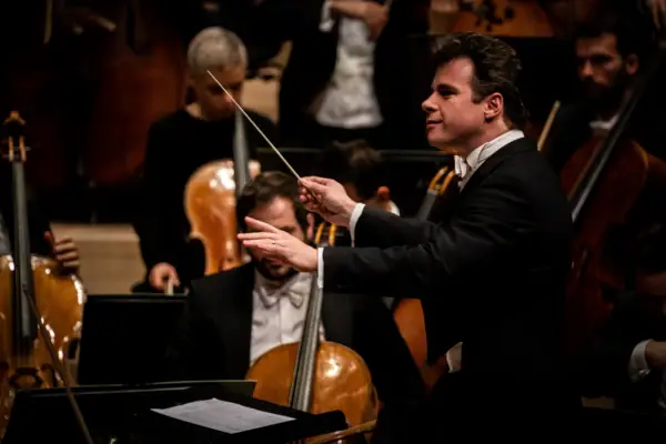 Jakub Hrůša Ein Mann dirigiert ein Orchester mit Streichinstrumenten.
