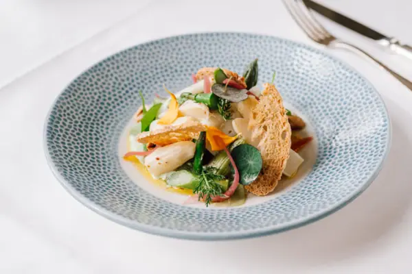 Ein Teller mit Essen auf einem Tisch mit Besteck und Garnitur