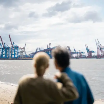 Hamburg Destination Ein Mann und eine Frau blicken auf die Elbe und den Hafen von Hamburg.