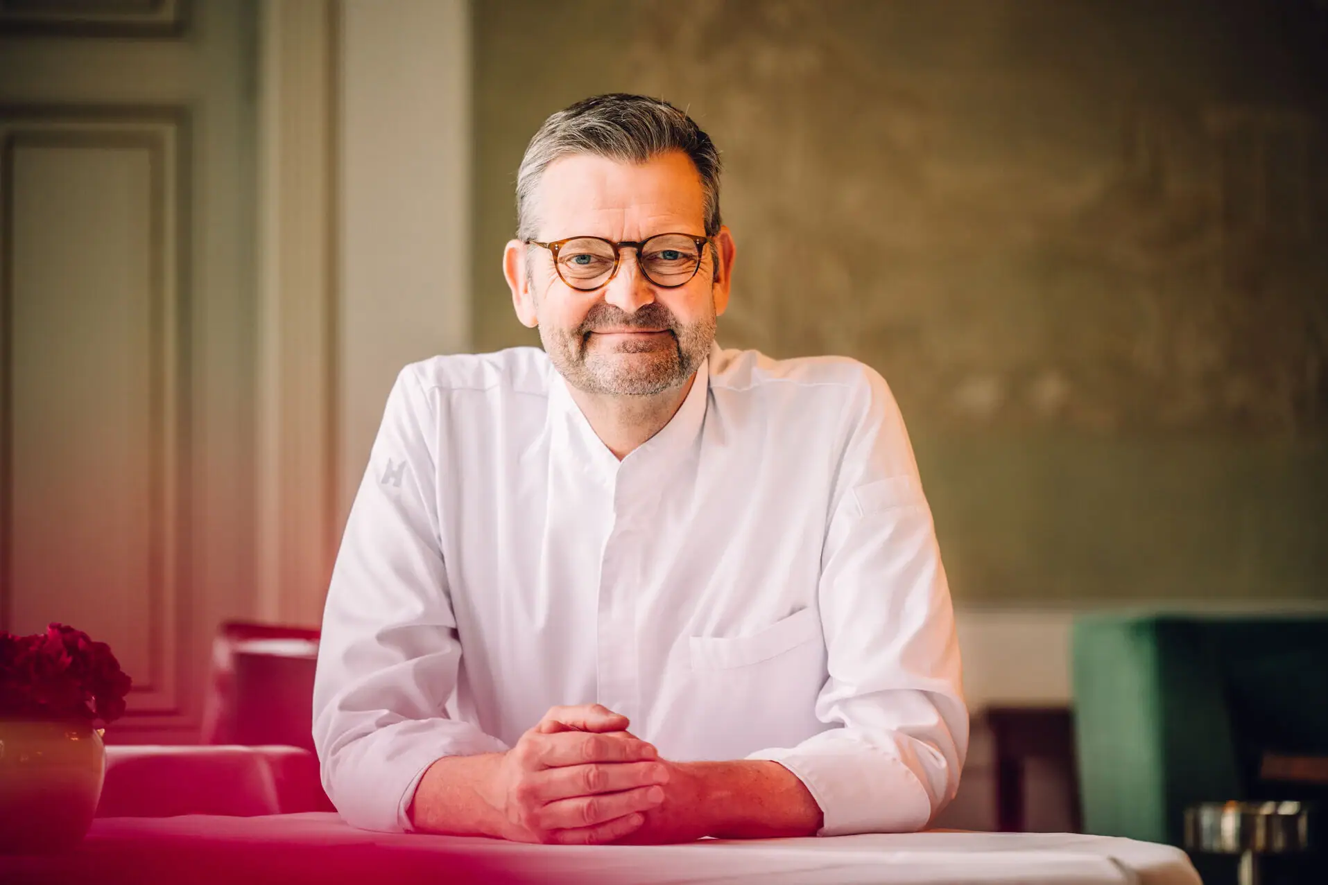 Thomas Martin Mann sitzt am Tisch und lächelt offen