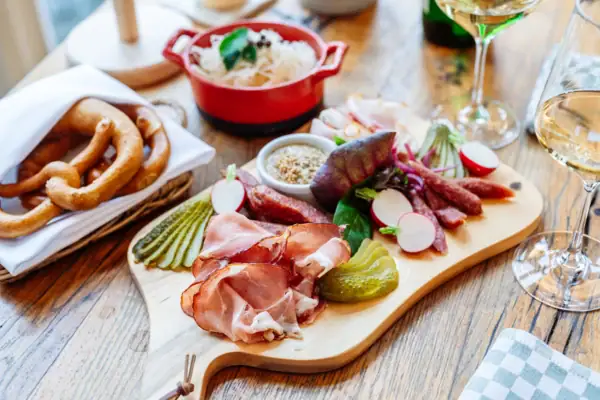 Holzbrett mit typisch österreichischer Brotzeit aus Wurst, Schinken und Gemüse.