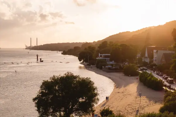 Strand mit Bäumen und Gebäuden an der Seite unter klarem Himmel.