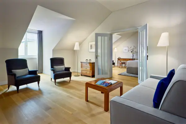 Ein großes Hotelzimmer mit einem Sofa und einem Tisch im vorderen Raum sowie einem separaten Schlafzimmer im Hintergrund.