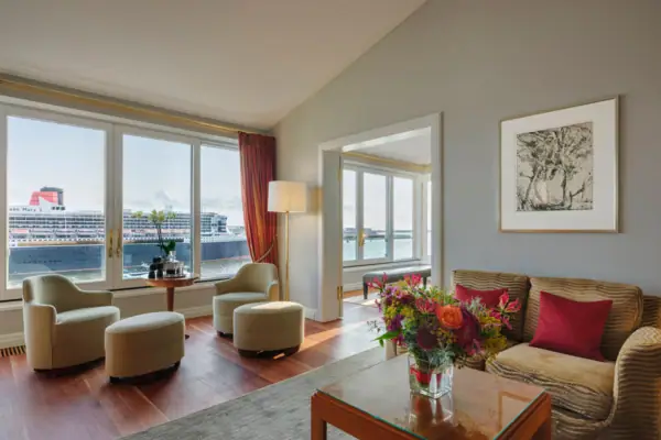 Wohnbereich mit Sofa und Sesseln einer Suite im Louis C. Jacob mit Blick auf die Elbe.
