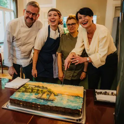 Eine Gruppe von Menschen steht um eine Torte.