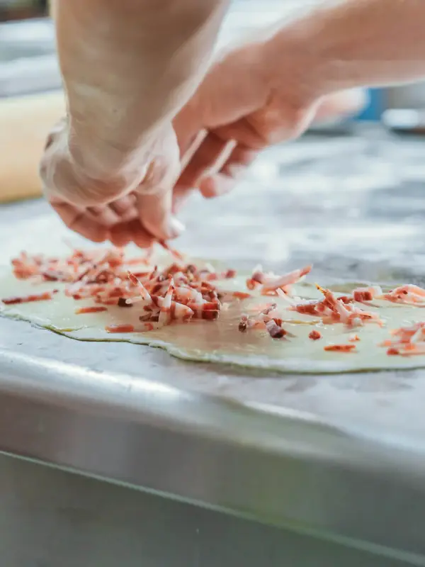 In der Küche bereitet ein Koch Flammkuchen zu.