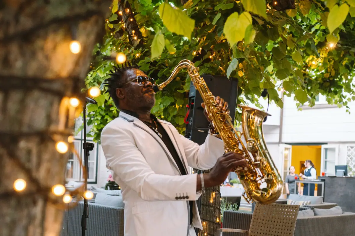 Saxophon-Spieler macht Musik unter Blätterdach der Lindenterrasse.