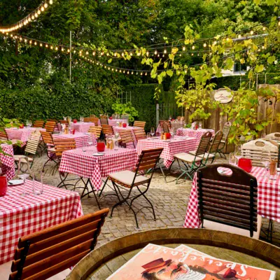 Biergarten der Weinwirtschaft Kleines Jacob mit Tische und Stühle im Freien sowie Lichterketten