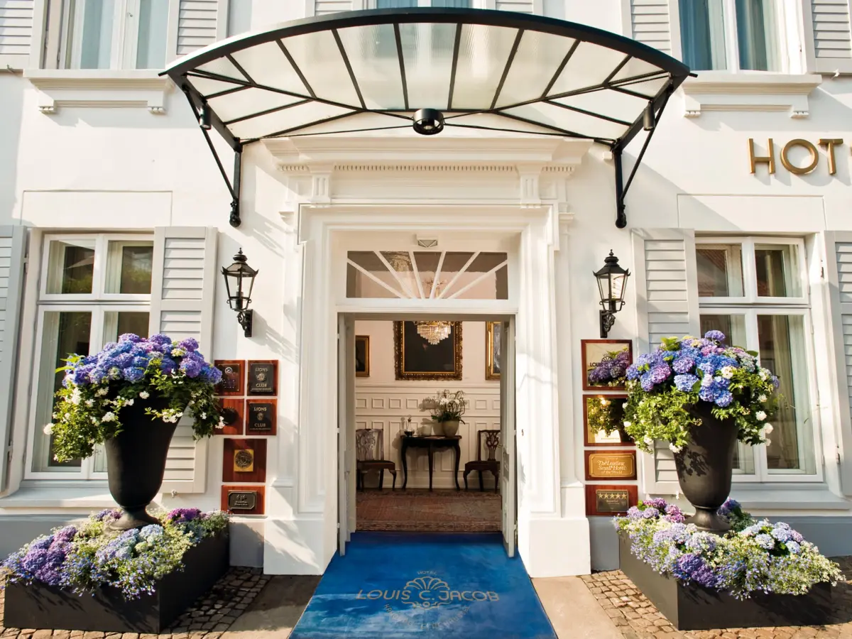 Eingang zum Hotel Louis C. Jacob dekoriert mit blauen Hortensiengestecken in hohen Vasen. 