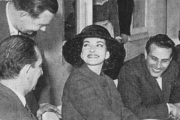 Schwarz-weiß Bild zeigt eine Gruppe aus 3 Männern und in der Mitte Maria Callas, die an einem Tisch sitzen.