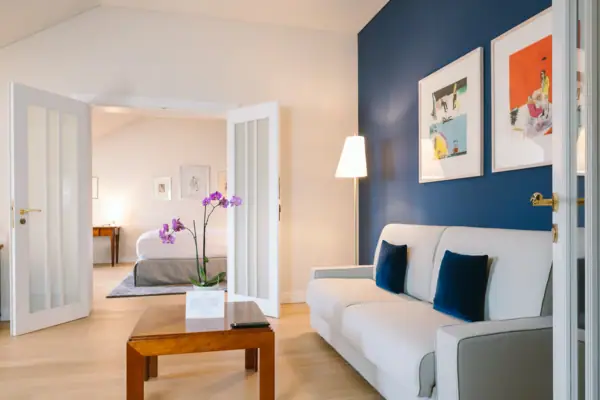 Ein großes Hotelzimmer mit einem Sofa und einem Tisch im vorderen Raum sowie einem separaten Schlafzimmer im Hintergrund.