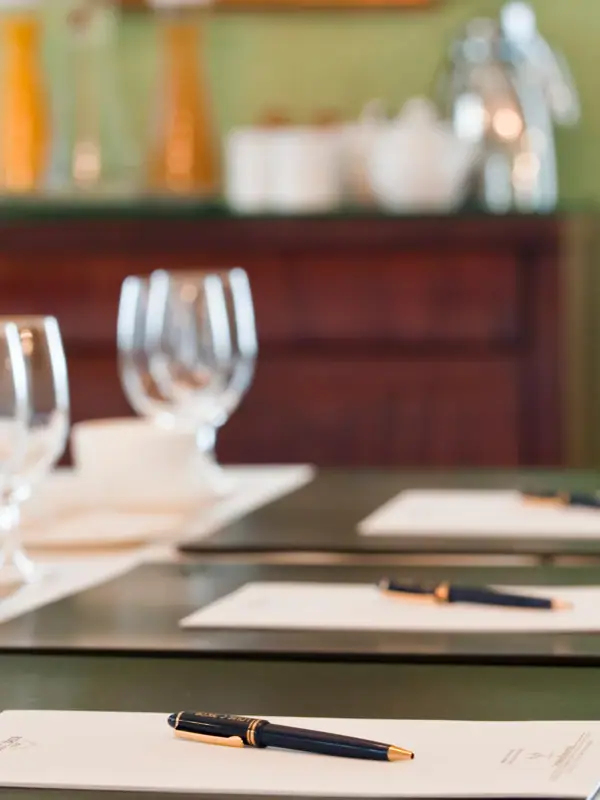 Ein Tisch vorbereitet für ein Meeting mit Stift und Notiz-Blocke auf jedem Teilnehmer-Platz.