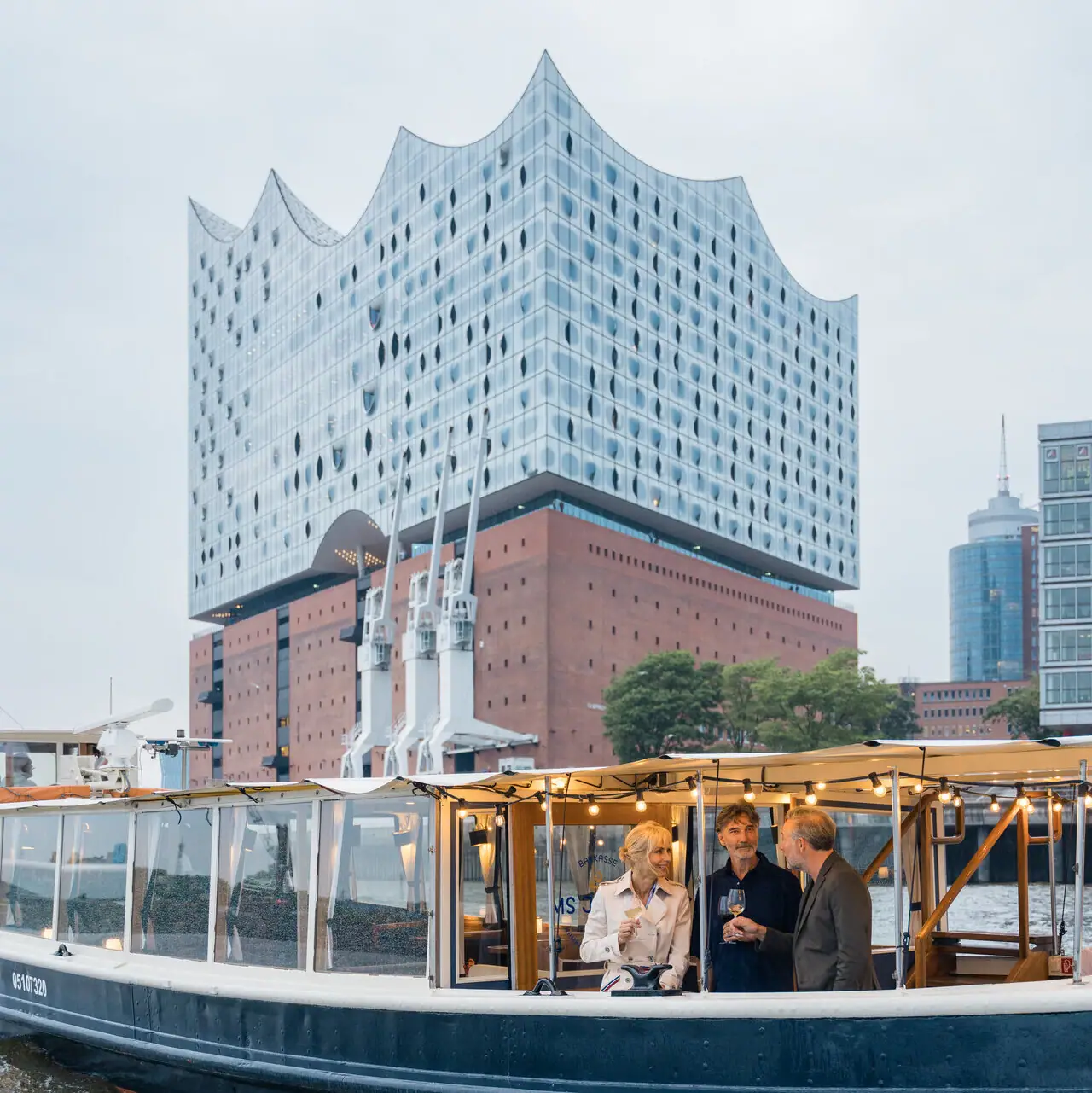 Eine Gruppe von Menschen auf einem Boot vor der Elbphillharmonie.